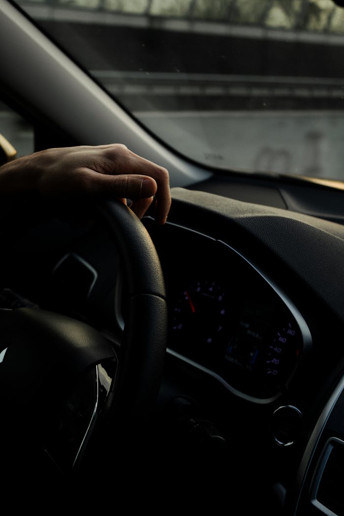 Close-up view of a hand on a car steering wheel while driving in Italy.