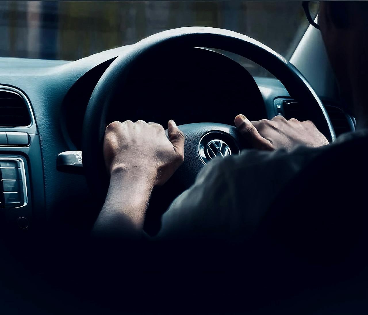 Focused view of hands on Volkswagen steering wheel, capturing driving experience.